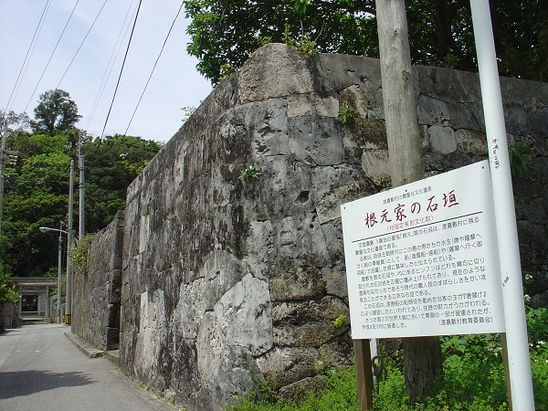 根元家の石垣の説明が書かれている看板と根元家の石垣を斜めから撮った写真