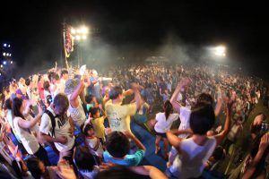 スポットライトの光の中大勢の人々が踊りを踊っている夜景の写真