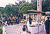戦没者慰霊祭で、多くの参列者が椅子に座り1人の参列者が白玉之塔の前で慰霊の言葉を読み上げている様子の写真